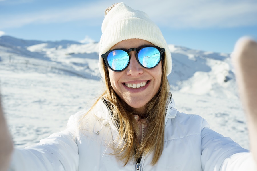 Zadovoljna žena sa sunčanim naočalama zimi