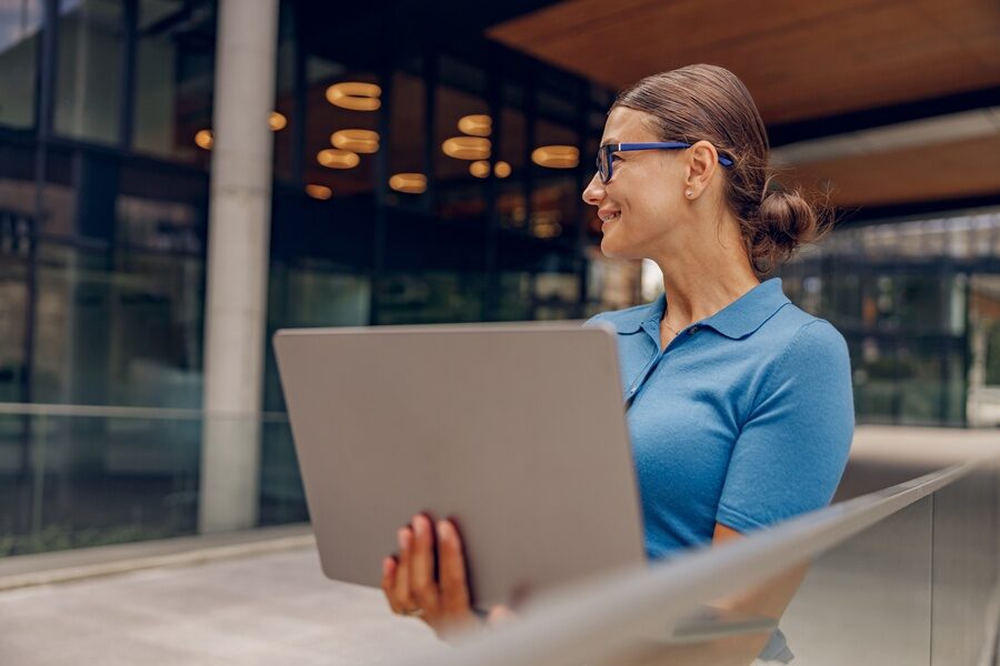 Ženska nasmijana osoba drži laptop u ruci 